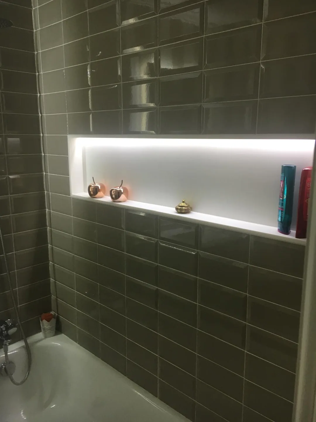 Baño con azulejo verde biselado y hornacina con luz indirecta