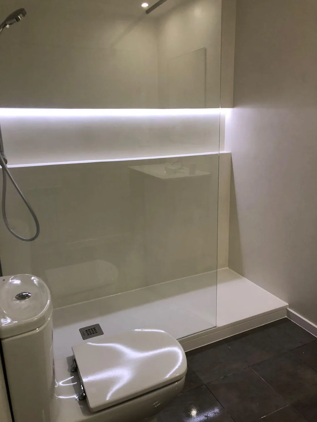 Ducha de obra en tono arena con plato blanco y hornacina iluminada